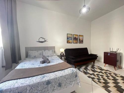 a bedroom with a bed and a black chair at Stúdio no Centro- Lapa, Consulado, Praia e Metrô! 1101 in Rio de Janeiro