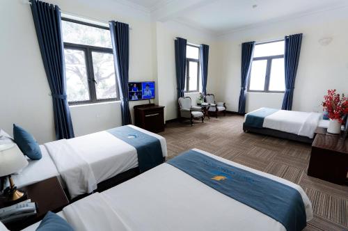 a hotel room with two beds and a desk at Bạch Đằng Hạ Long Hotel in Ha Long