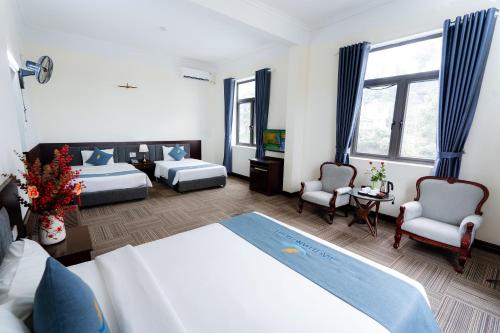 a hotel room with two beds and two chairs at Bạch Đằng Hạ Long Hotel in Ha Long