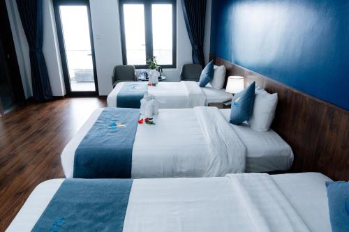 a hotel room with three beds with blue walls at Bạch Đằng Hạ Long Hotel in Ha Long