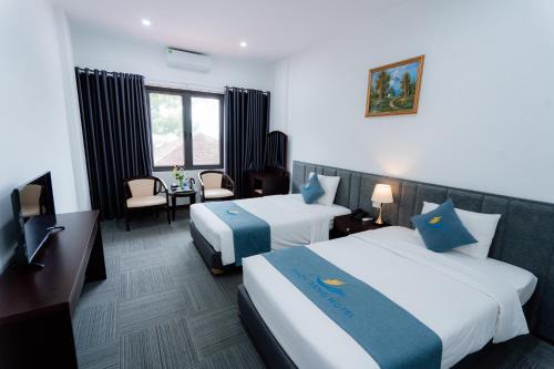 a hotel room with two beds and a desk at Bạch Đằng Hạ Long Hotel in Ha Long