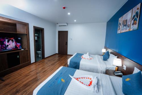 a hotel room with two beds and a tv at Bạch Đằng Hạ Long Hotel in Ha Long