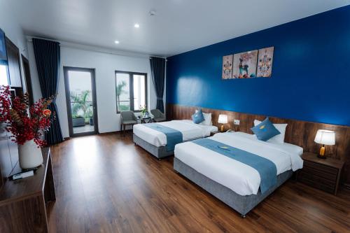 a bedroom with two beds and a blue wall at Bạch Đằng Hạ Long Hotel in Ha Long