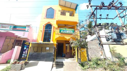 a yellow building with a sign in front of it at Uddish Residency in Virāmpattinam