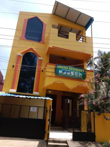 a yellow building with a sign in front of it at Uddish Residency in Virāmpattinam