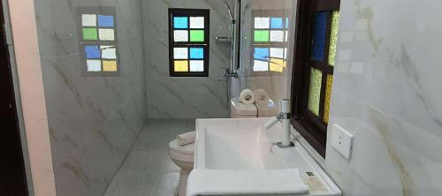 a white bathroom with a toilet and a sink at Vida Pacifica Resort & Hotel by RedDoorz in Mabini