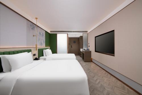a hotel room with two beds and a flat screen tv at Mehood Lestie Hotel, Nanjing Xinjiekou Subway Station in Nanjing