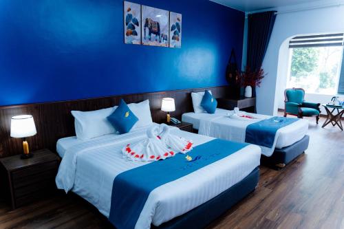 a hotel room with two beds with blue walls at Bạch Đằng Hạ Long Hotel in Ha Long