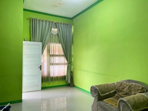 a green room with a couch and a window at Puni Anjung Homestay in Panjalu