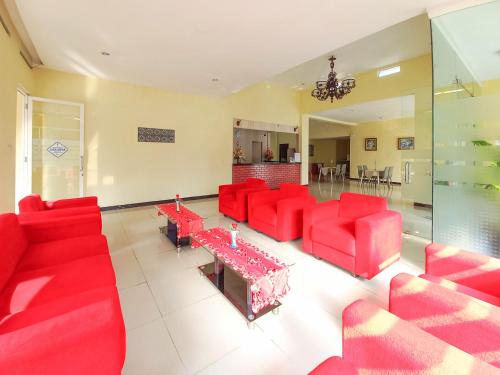 a living room with red couches and a table at Hotel Palem Sari Syariah Batu RedPartner in Punten