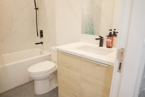 a white bathroom with a toilet and a sink at New Luxury Walkout Suite Near University-BY ROOM in Calgary