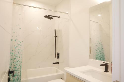 a white bathroom with a shower and a sink at New Luxury Walkout Suite Near University-BY ROOM in Calgary