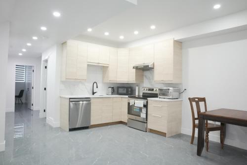 a kitchen with white cabinets and a wooden table at New Luxury Walkout Suite Near University-BY ROOM in Calgary