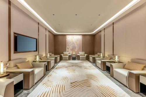 a waiting room with white chairs and a flat screen tv at Holiday Inn Fuzhou Exhibition Center in Fuzhou