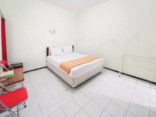 a bedroom with a bed and a red chair at Hotel Palem Sari Syariah Batu RedPartner in Punten