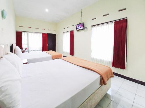 a bedroom with two beds and a television in it at Hotel Palem Sari Syariah Batu RedPartner in Punten