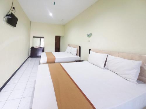 a hotel room with two beds and a television at Hotel Palem Sari Syariah Batu RedPartner in Punten