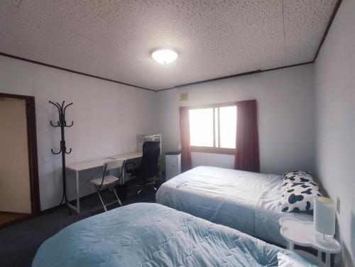 札幌市にあるMoio Homestayのベッド2台と机と窓のある寝室