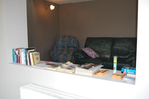 a shelf with books and a couch and a chair at Ferme du Charme in Moustier