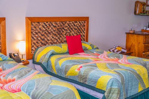 a bedroom with two beds and a red pillow at Lost Iguana Resort and Spa in Fortuna