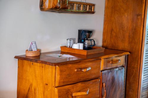 a wooden cabinet with a coffee maker on top of it at Lost Iguana Resort and Spa in Fortuna