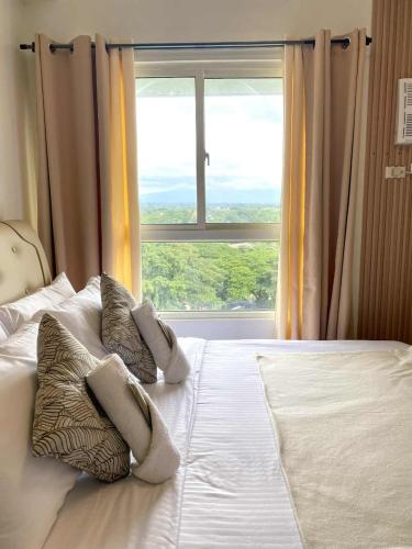 a bedroom with a bed with pillows and a window at H4R1 Luxe Haven in Bacolod