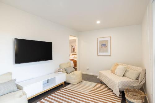 a living room with a flat screen tv on a wall at PI Hot Springs Retreat1 in Surf Beach