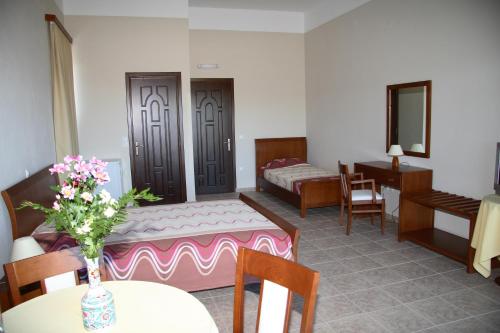 a room with a bed and a table with flowers on it at Calypso Apartments in Vathi, Ithaka