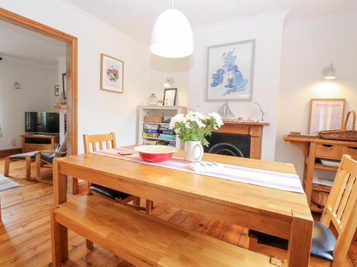 a dining room with a wooden table with flowers on it at Driftwood Cottage in Heacham
