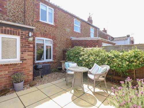 a patio with a table and chairs in front of a brick building at Driftwood Cottage in Heacham