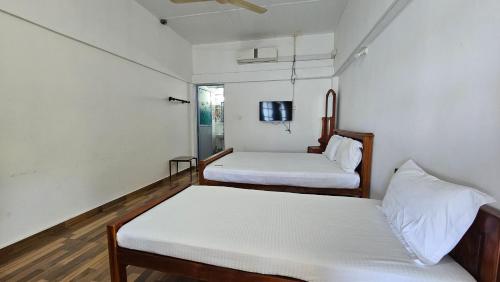 a room with two beds and a tv on the wall at Lagoon Breeze Resort in Batticaloa