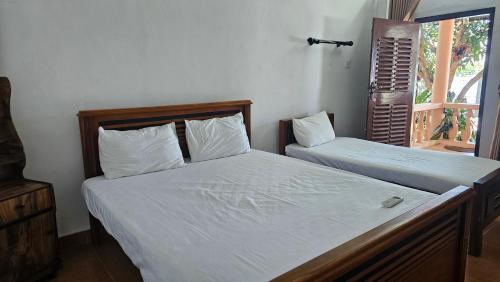 a bedroom with two beds with white sheets and a window at Lagoon Breeze Resort in Batticaloa