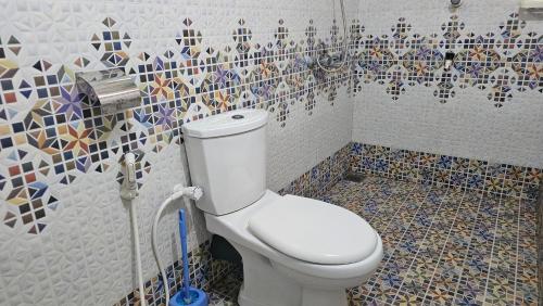 a bathroom with a toilet and a mosaic wall at Lagoon Breeze Resort in Batticaloa