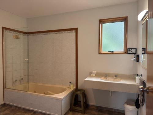 a bathroom with a bath tub and a sink at ASURE Ambassador Motor Lodge in Oamaru