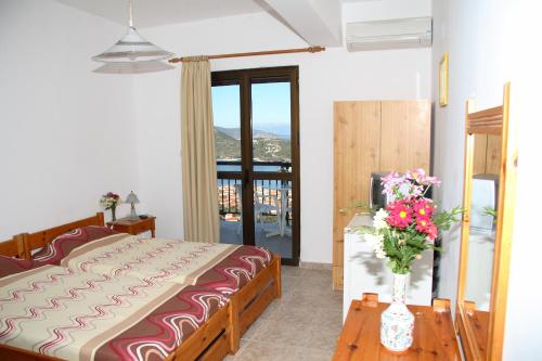 a bedroom with a bed and a vase of flowers on a table at Calypso Apartments in Vathi, Ithaka
