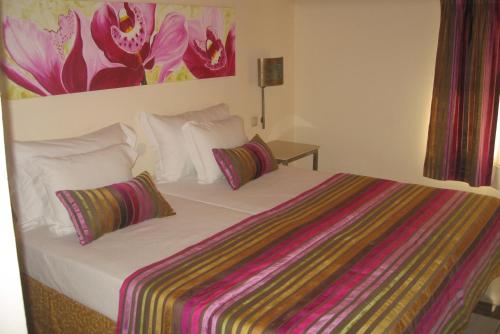 a bed with two pillows and a painting on the wall at Hospedaria Frangaria in Faro