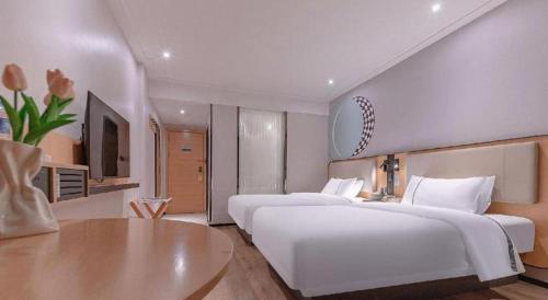 a large white bedroom with two beds and a table at City Comfort Inn Liuzhou High-speed Railway Station in Liuzhou