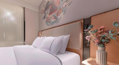 a bedroom with a white bed with a vase of flowers at City Comfort Inn Liuzhou High-speed Railway Station in Liuzhou