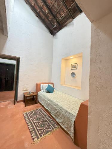 a bedroom with a bed in a room with a rug at Caju Grove - The Big Yellow Goan House in Guirim