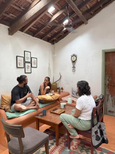 a group of people sitting around a table in a room at Caju Grove - The Big Yellow Goan House in Guirim