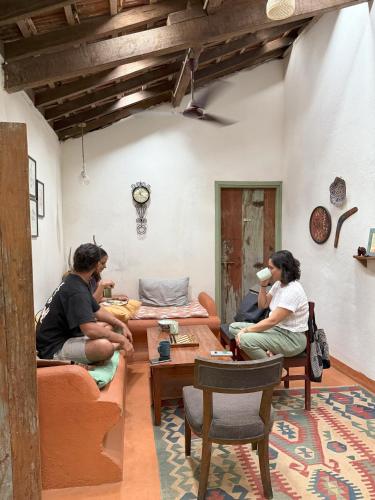 a group of people sitting on couches in a living room at Caju Grove - The Big Yellow Goan House in Guirim