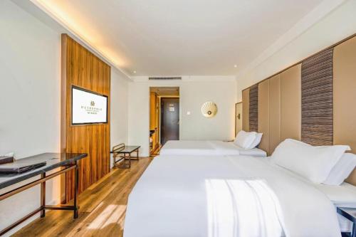 a hotel room with two beds and a desk at Jinjiang Metropolo Haikou East High Speed Railway Station Normal University in Haikou
