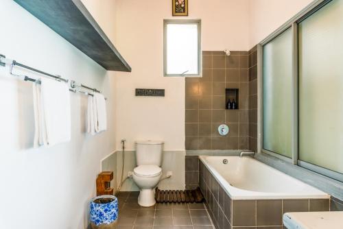 a bathroom with a toilet and a tub and a sink at Marleys Beach House in Talpe