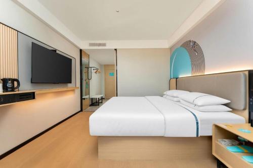 a bedroom with a white bed and a flat screen tv at City Comfort Inn Shiyan Wudang Mountain in Danjiangkou