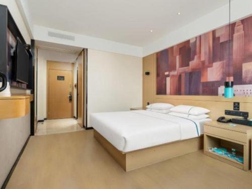 a bedroom with a large white bed and a television at City Comfort Inn Shiyan Wudang Mountain in Danjiangkou