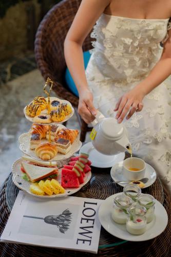 Eine Frau im Brautkleid serviert Essen auf einem Tisch. in der Unterkunft Sea Front Apartment & Spa Da Nang in Đà Nẵng