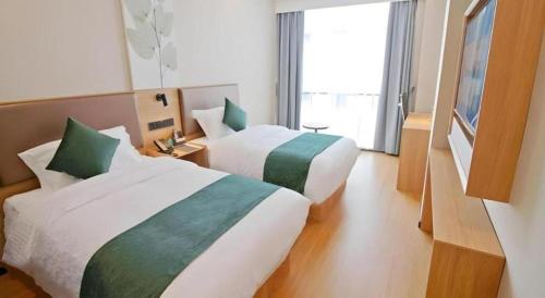 a hotel room with two beds and a window at GreenTree Inn Express Zhangjiagang Hexing Town Shazhou Professional Institue of Technology in Qiwei