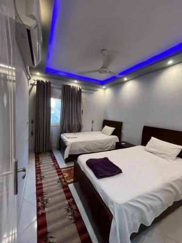 two beds in a room with a blue ceiling at Roma Apartment LXR in Luxor