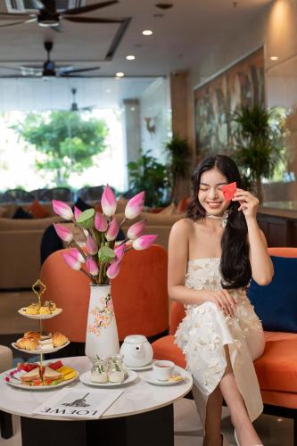 a woman in a white dress is holding a red bow at Sea Front Apartment & Spa Da Nang in Danang