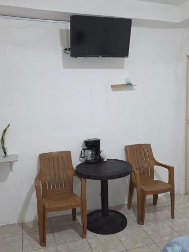 mesa con 2 sillas y TV en la pared en Yulis Home 1, en Retalhuleu